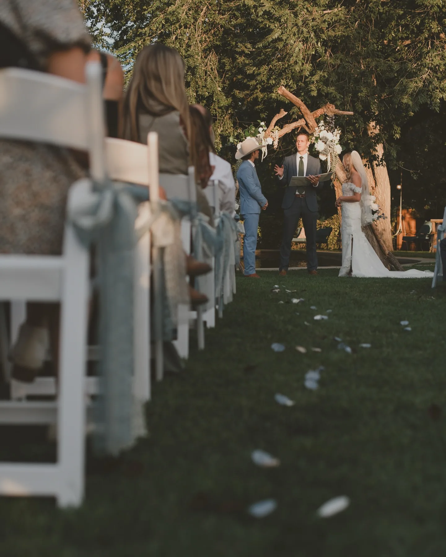 Guests seated along an aisle at golden hour as a couple stands at the altar